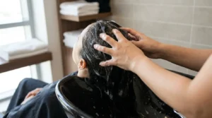 how to get rid of dandruff: hairdresser massaging shampoo into a clients scalp at a Dubai salon wash basin
